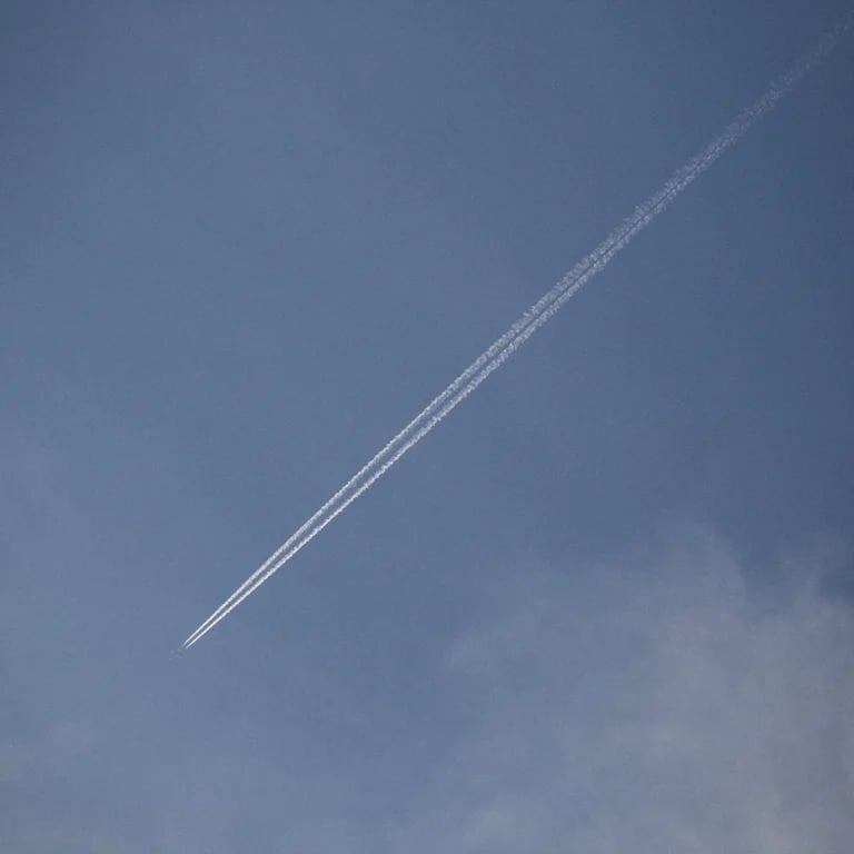 A contrail stretching diagonally across a blue sky