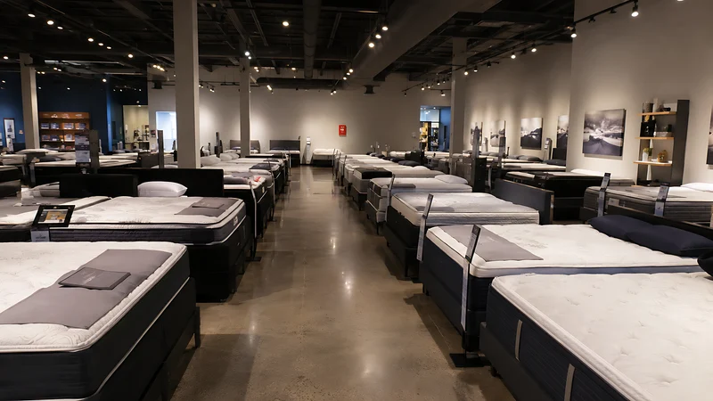 A mattress showroom with rows of beds